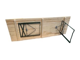 Table pliante en pin massif déployée dans une salle des fêtes communale, configuration 8 places avec piétement acier époxy vert